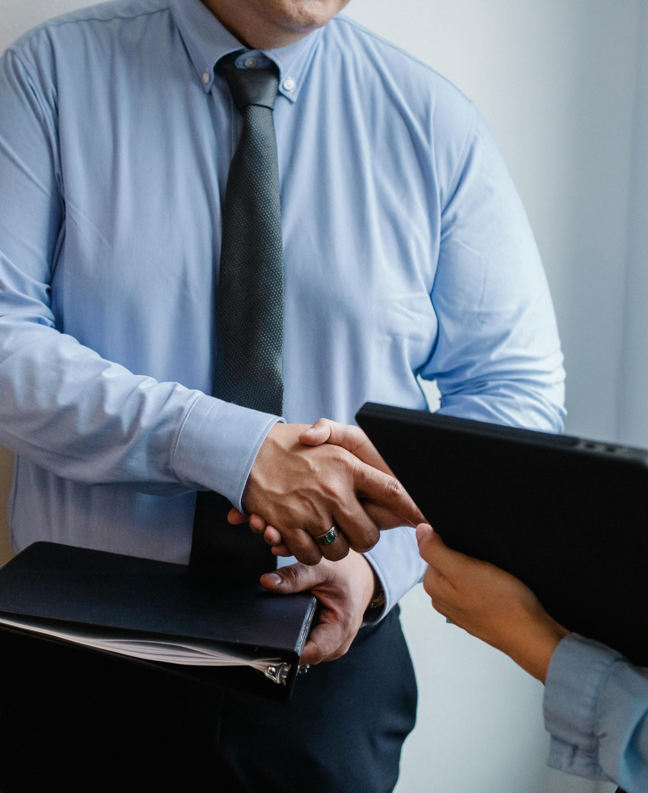 Business handshake between colleagues in a formal office meeting setting.